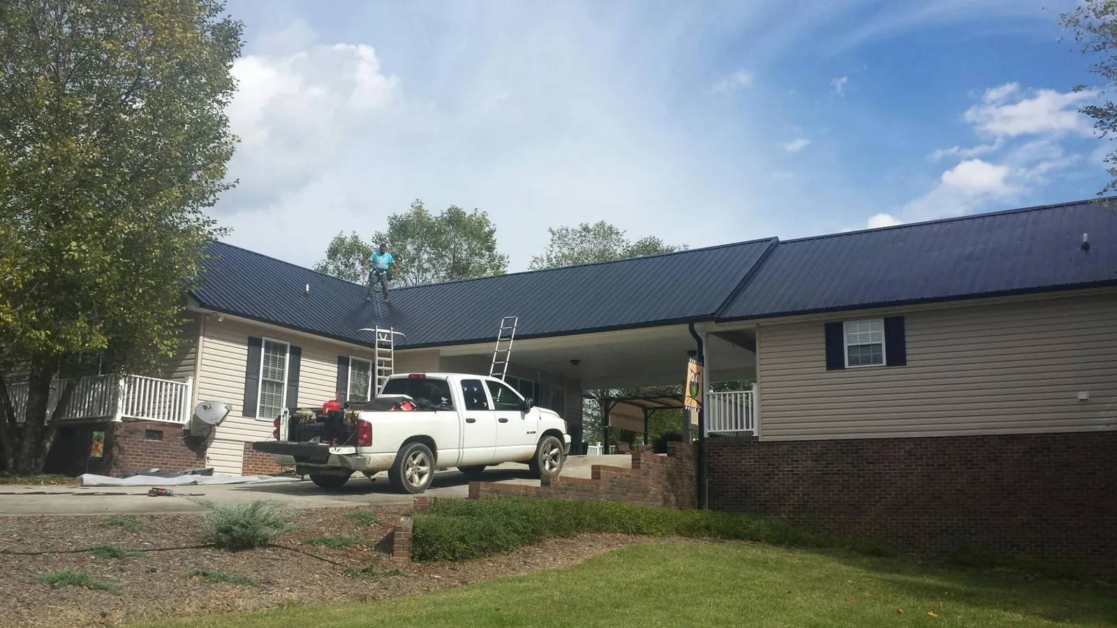 Black metal roof over a home and attached breezeway with ladders set in Wells