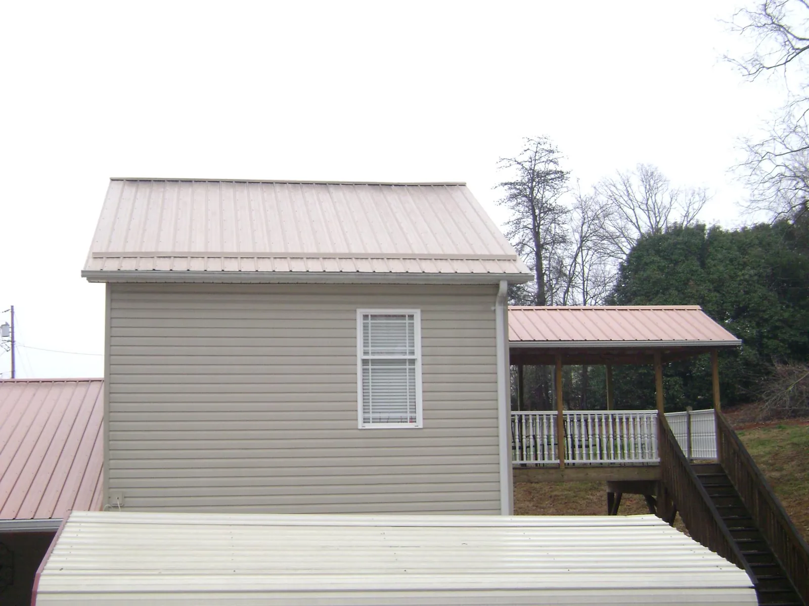 Tan metal roofs on a two story addition and attached porch, from a Roof Replacement job in Wells